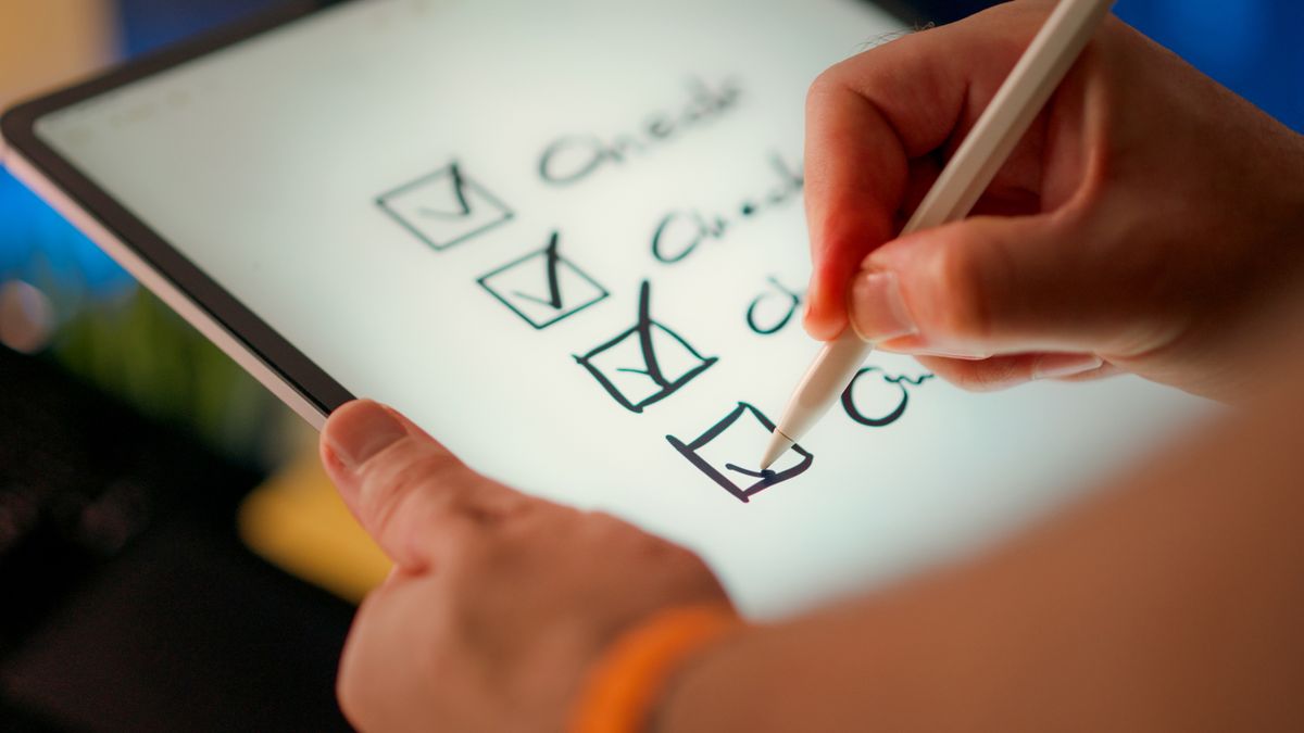 A hand ticking off items on a digital checklist on a tablet, representing the components of an affordable SEO package. Photo from Pexels.