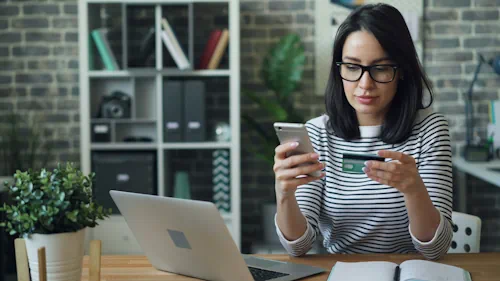 A lady is doing online shopping and olding a credit card. Sevinu, Shopify website designer in Brisbane. Photo from Pexels.